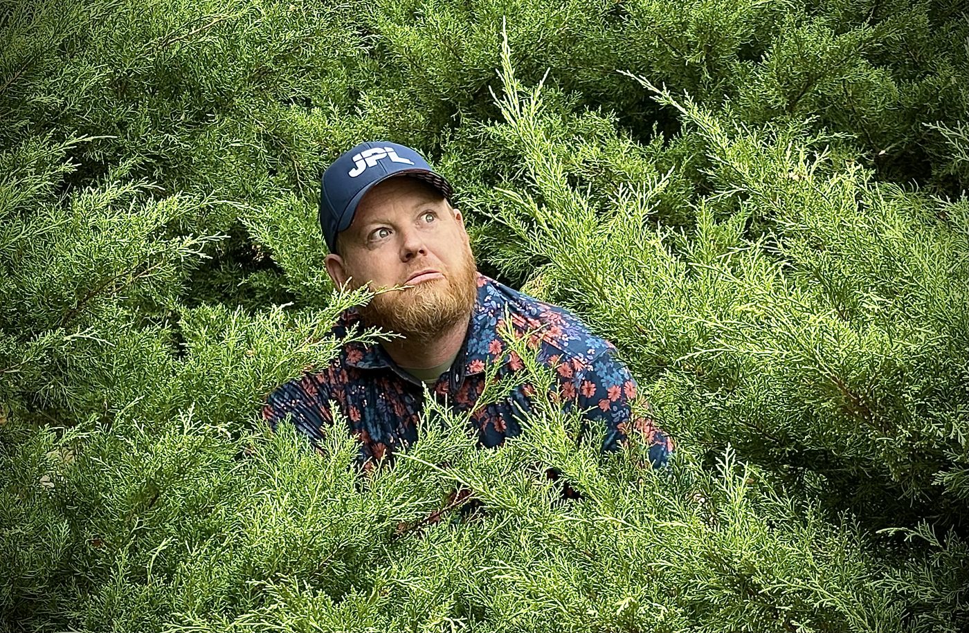 Ben in a JPL cap, hiding in a hedge