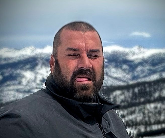 A bearded man identified only as Neighbor, squinting in the mountains